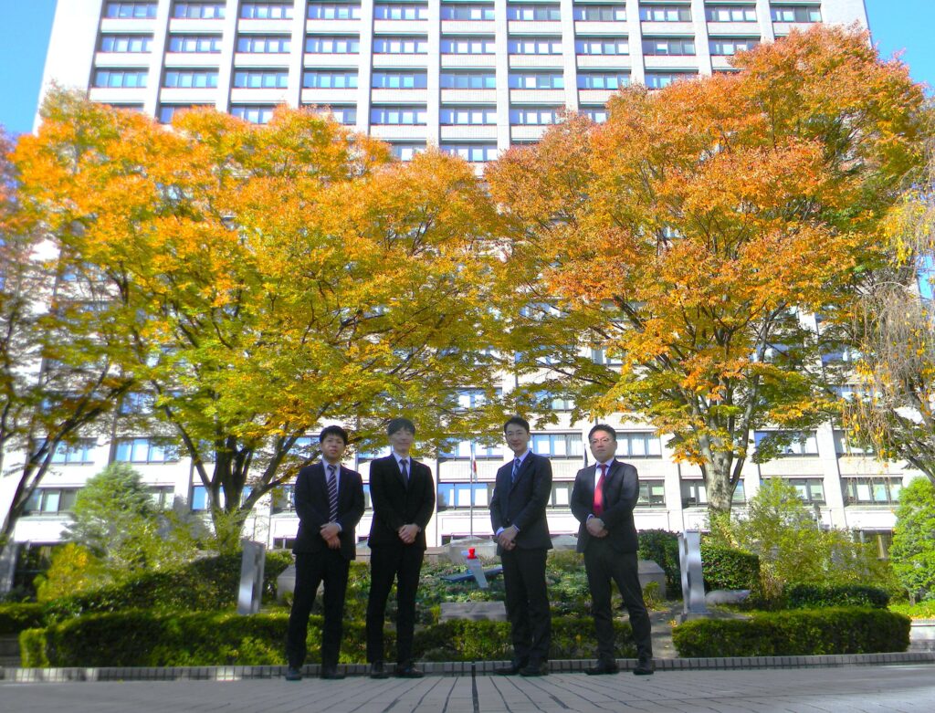 県庁舎の前で事務局の皆さんが映っているお写真